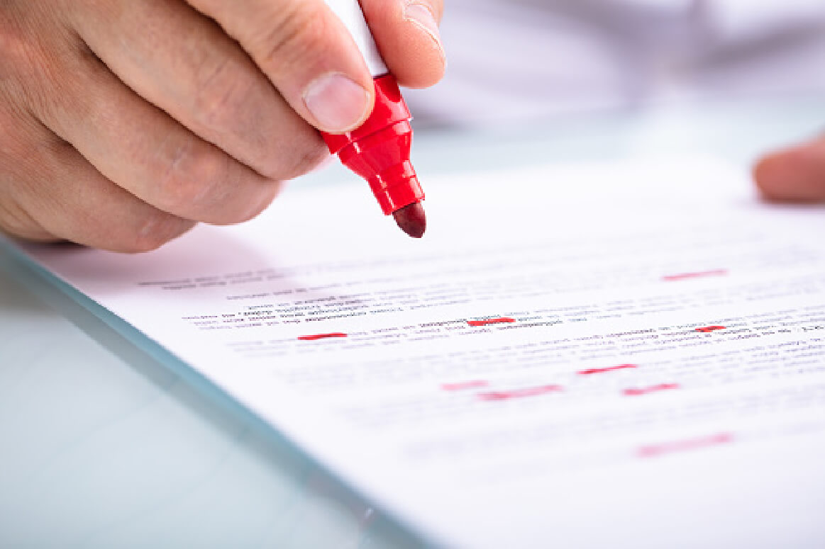 close up of hand editing a paper with red marker