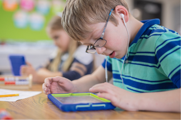 close up of young student at a desk, wearing ear buds and working on a tablet